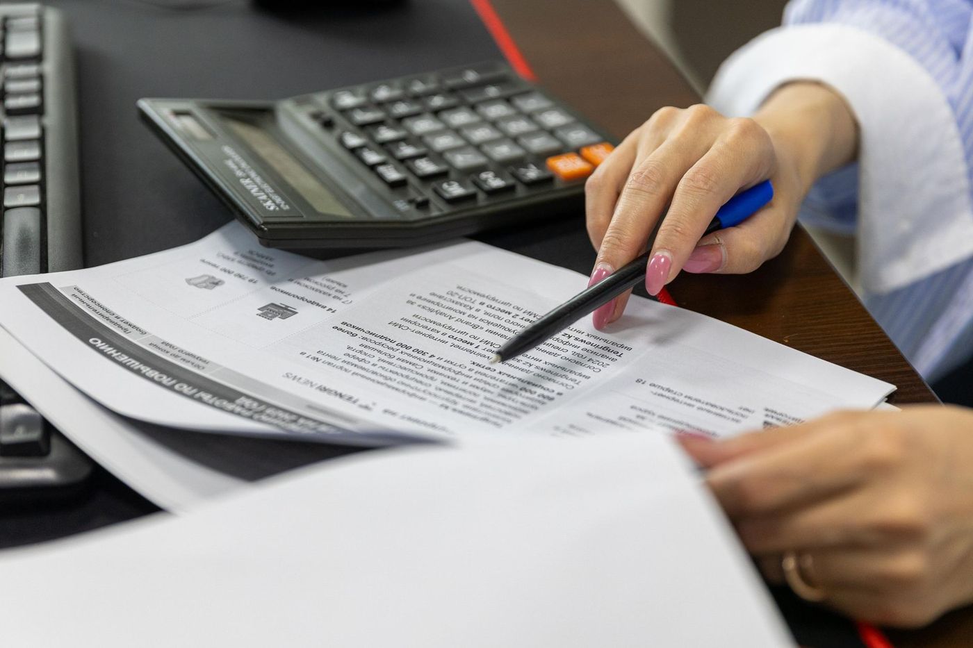 Manos revisando un documento tributario con calculadora sobre el escritorio